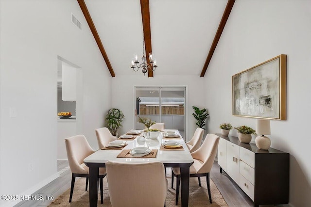 dining space with wood-type flooring, an inviting chandelier, and vaulted ceiling with beams