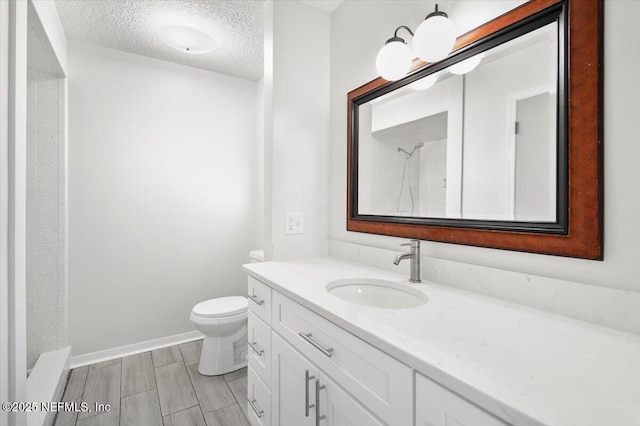 bathroom featuring a textured ceiling, vanity, toilet, and walk in shower