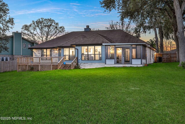 994 Lakeridge Dr, Orange Park, FL 32065 - back of property at dusk with a chimney, a shingled roof, a lawn, fence, and a deck