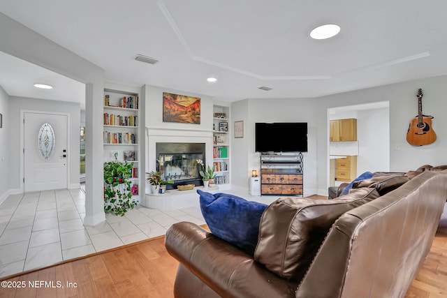 994 Lakeridge Dr, Orange Park, FL 32065 - living area featuring built in features, a glass covered fireplace, light wood-type flooring, and visible vents