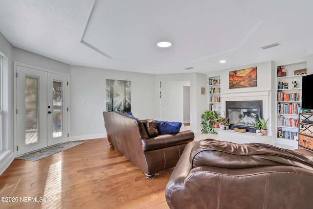 994 Lakeridge Dr, Orange Park, FL 32065 - living room featuring visible vents, built in features, a glass covered fireplace, light wood-style flooring, and french doors