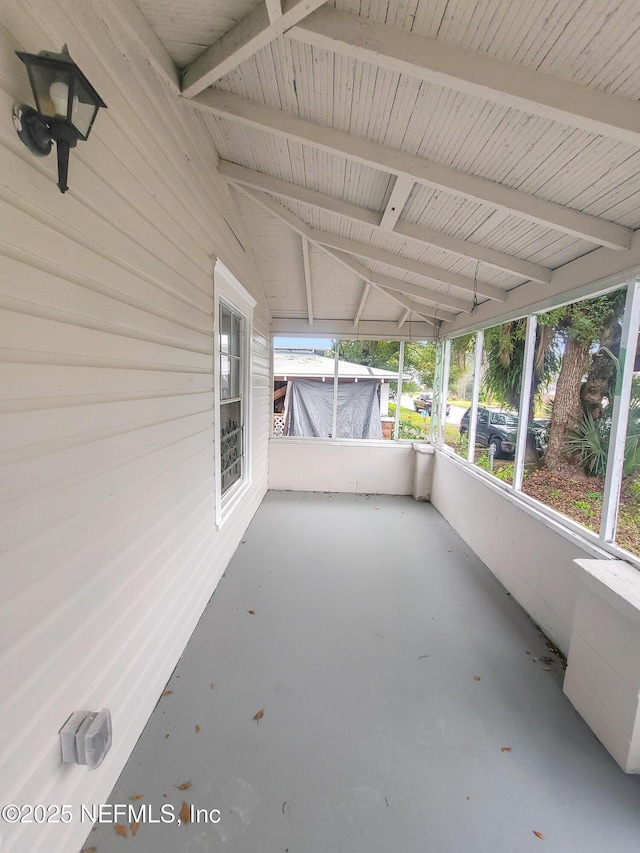 unfurnished sunroom with lofted ceiling with beams