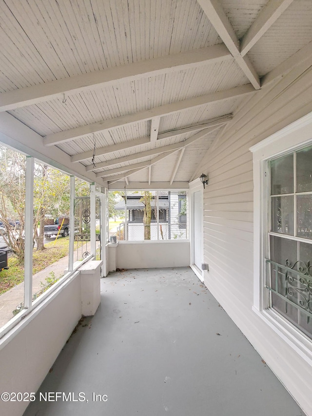 unfurnished sunroom with lofted ceiling with beams