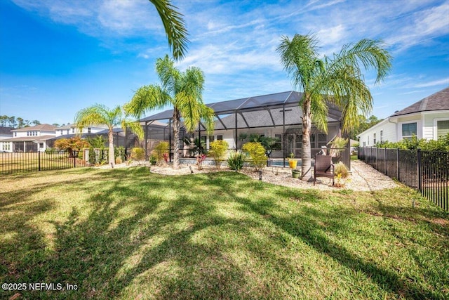 rear view of property featuring a lanai, a fenced backyard, and a lawn