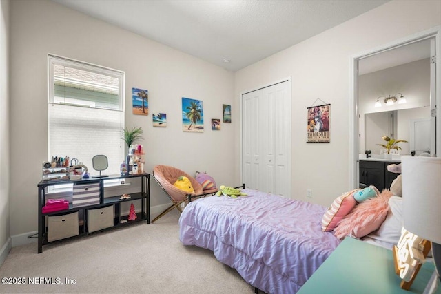 bedroom with a closet, carpet, ensuite bath, and baseboards