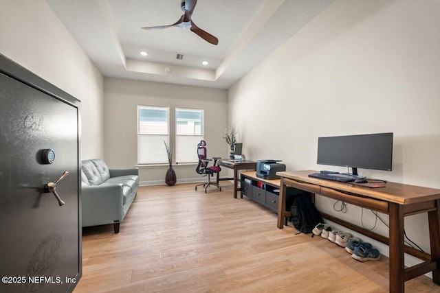 office space with ceiling fan, recessed lighting, baseboards, light wood finished floors, and a raised ceiling