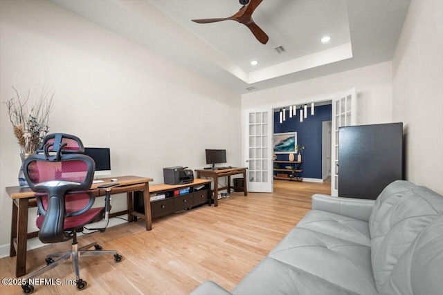 home office featuring ceiling fan, recessed lighting, light wood-style floors, french doors, and a raised ceiling