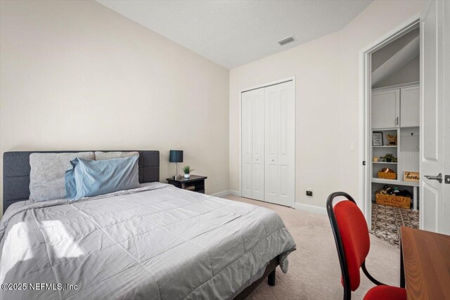 bedroom featuring visible vents, baseboards, vaulted ceiling, a closet, and carpet