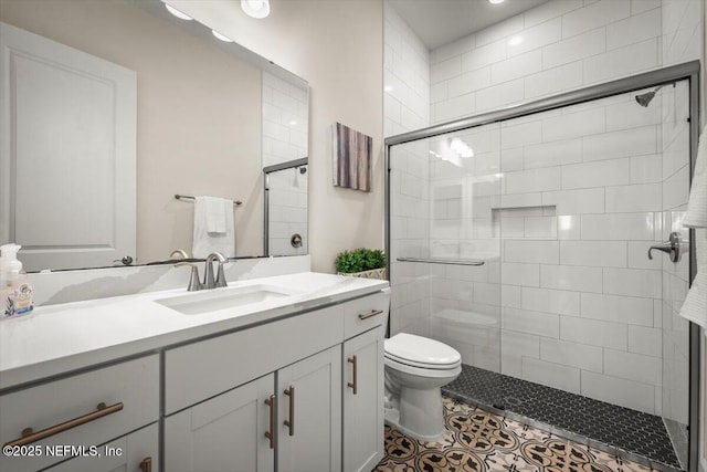 full bathroom featuring toilet, tile patterned floors, tiled shower, and vanity