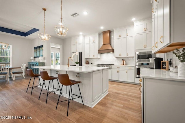 kitchen with light countertops, appliances with stainless steel finishes, custom exhaust hood, and visible vents