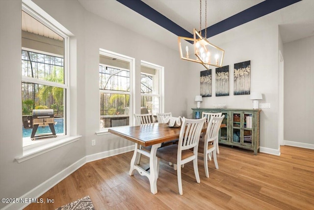 dining area with baseboards, a healthy amount of sunlight, a notable chandelier, and light wood finished floors