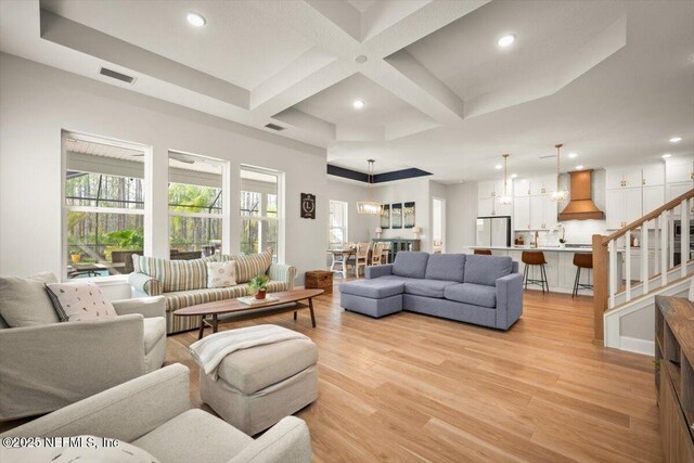 living area with recessed lighting, visible vents, light wood-style flooring, coffered ceiling, and stairs