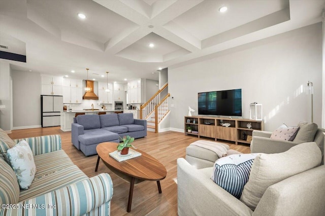 living room featuring recessed lighting, coffered ceiling, baseboards, stairs, and light wood finished floors