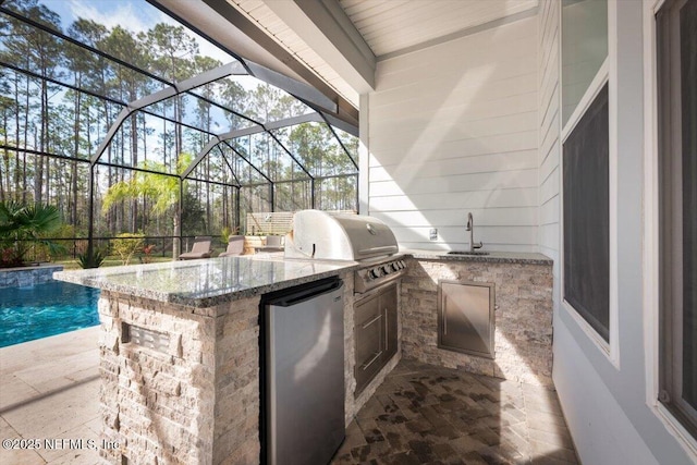 view of patio featuring glass enclosure, an outdoor pool, a sink, and area for grilling