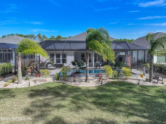 back of property with a patio area, glass enclosure, a fenced in pool, and a yard