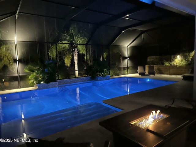 pool at night with a lanai and an outdoor pool