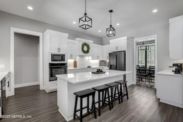 kitchen featuring a kitchen island, white cabinets, hanging light fixtures, light countertops, and black appliances