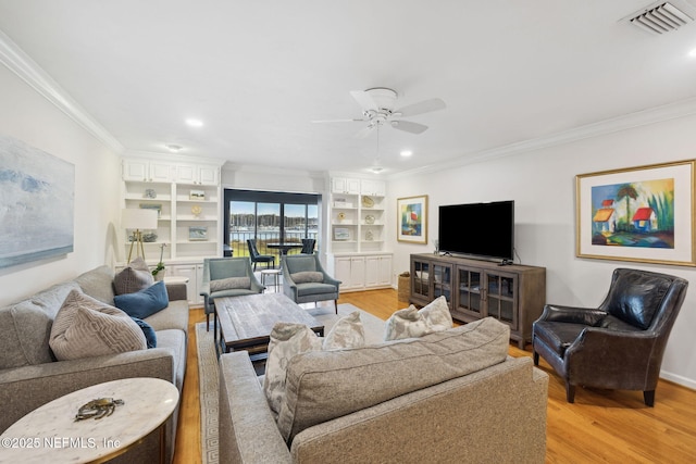 living room with light wood-type flooring, ceiling fan, crown molding, and built in features