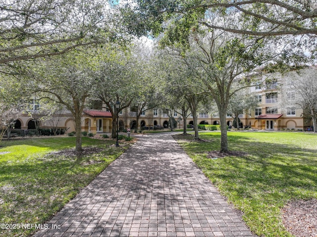 view of community featuring decorative driveway and a lawn