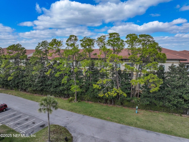 view of property's community featuring uncovered parking, a lawn, and a residential view