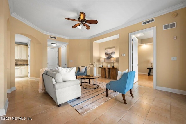 living area featuring arched walkways, visible vents, and crown molding