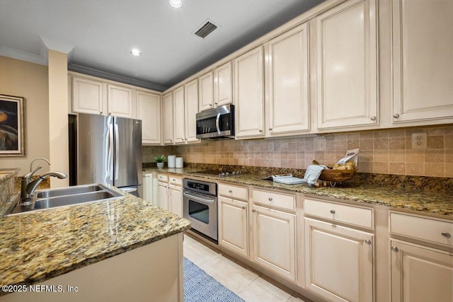 kitchen with appliances with stainless steel finishes, a sink, visible vents, and tasteful backsplash