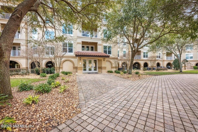 multi unit property with french doors, a tile roof, and stucco siding