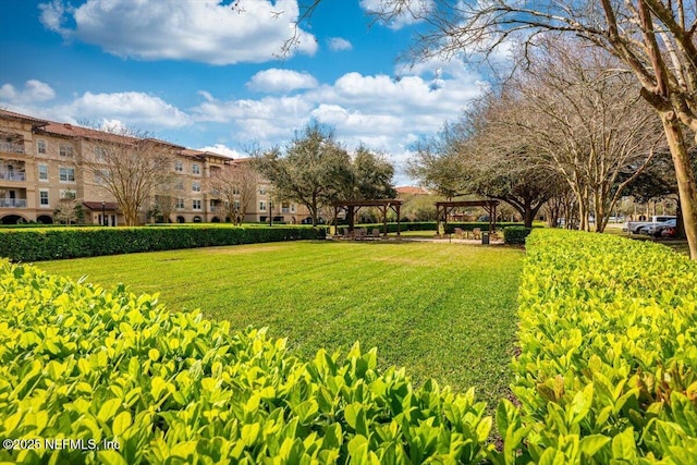 view of property's community with a yard and a pergola