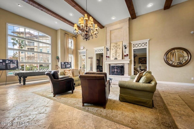 living room featuring a chandelier, a high ceiling, baseboards, beamed ceiling, and a tiled fireplace