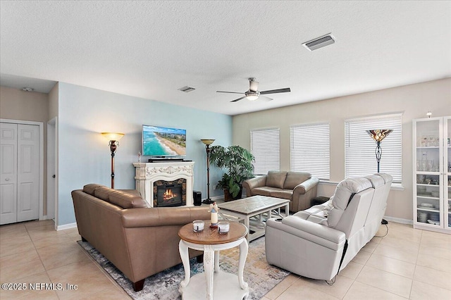 living room featuring ceiling fan, light tile patterned flooring, and a textured ceiling