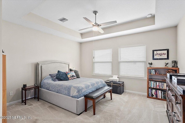 carpeted bedroom featuring a textured ceiling, ceiling fan, and a raised ceiling