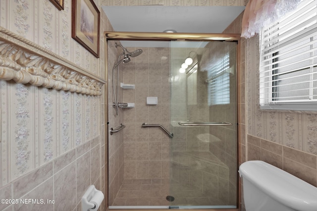 bathroom with toilet, wallpapered walls, and a stall shower