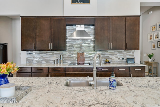 95384 Bermuda Dr, Fernandina Beach, FL 32034 - kitchen featuring backsplash, dark brown cabinets, wall chimney range hood, a sink, and light stone countertops
