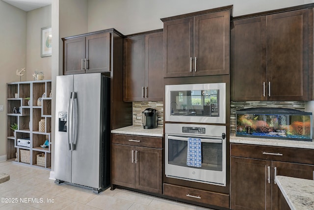 95384 Bermuda Dr, Fernandina Beach, FL 32034 - kitchen with stainless steel appliances, dark brown cabinets, backsplash, light stone countertops, and light tile patterned floors
