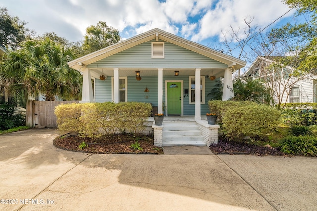 bungalow-style home with covered porch and fence