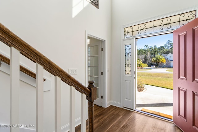 entryway featuring dark wood-type flooring, baseboards, a high ceiling, and stairs