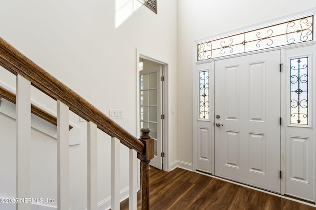 entrance foyer featuring dark wood finished floors, a towering ceiling, and baseboards