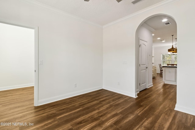 unfurnished room with baseboards, crown molding, arched walkways, and dark wood-style flooring