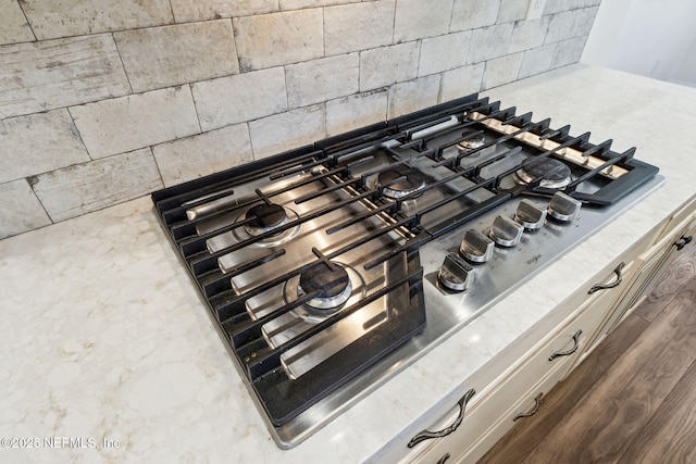 details featuring light countertops, stainless steel gas stovetop, and backsplash