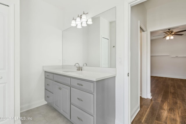 bathroom featuring ceiling fan, wood finished floors, vanity, baseboards, and a closet