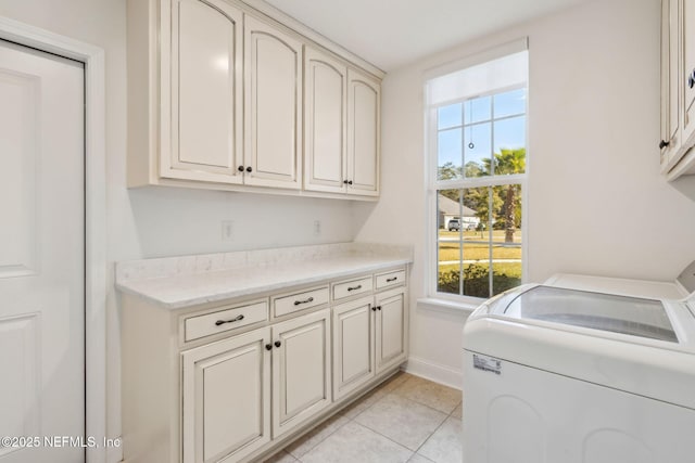 clothes washing area with cabinet space, baseboards, washer and dryer, and light tile patterned flooring