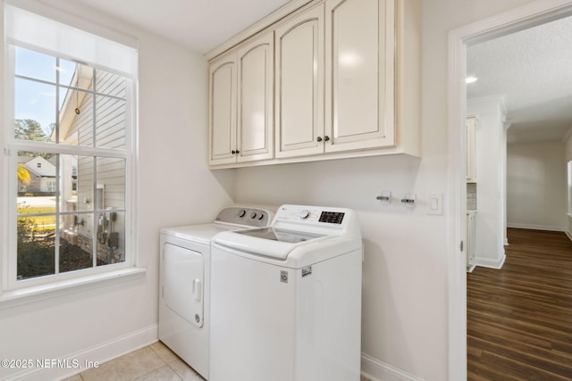 laundry area featuring cabinet space, washer and clothes dryer, baseboards, and light tile patterned flooring