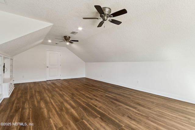 additional living space with baseboards, visible vents, lofted ceiling, dark wood-style floors, and a textured ceiling