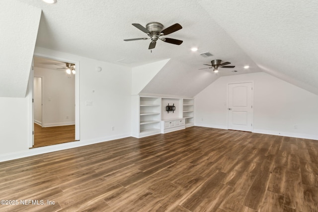 bonus room with a textured ceiling, dark wood-style floors, and visible vents