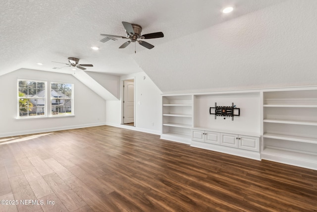 additional living space with built in shelves, vaulted ceiling, a textured ceiling, wood finished floors, and baseboards