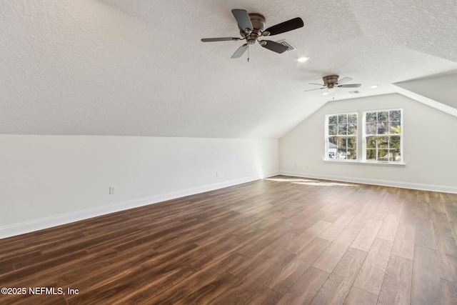 bonus room with lofted ceiling, dark wood-type flooring, a textured ceiling, and baseboards