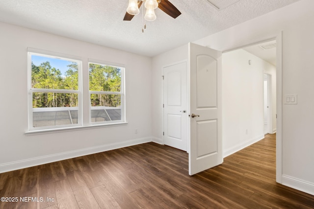 unfurnished room with dark wood-style floors, visible vents, a textured ceiling, and baseboards