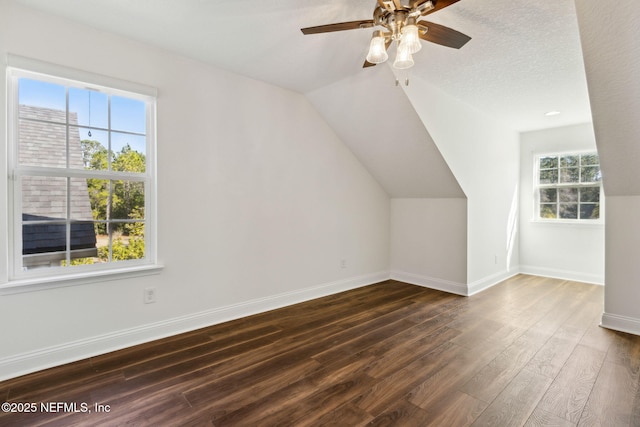 bonus room with dark wood finished floors, lofted ceiling, ceiling fan, a textured ceiling, and baseboards