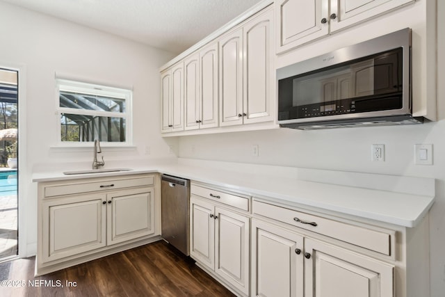 kitchen featuring light countertops, appliances with stainless steel finishes, a sink, and dark wood finished floors