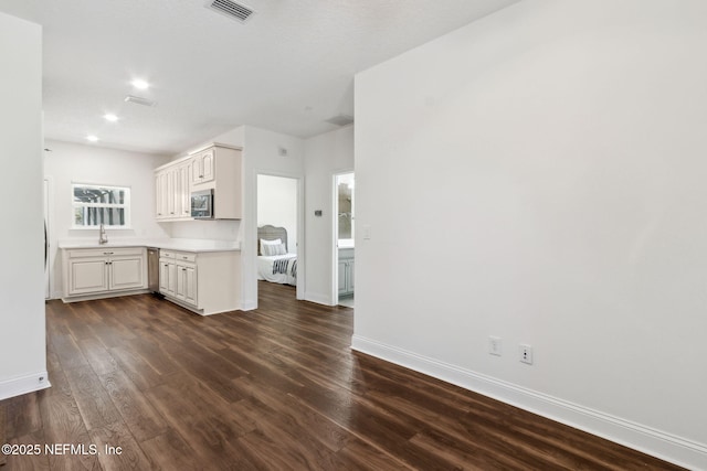 interior space featuring visible vents, white cabinets, dark wood finished floors, stainless steel microwave, and light countertops